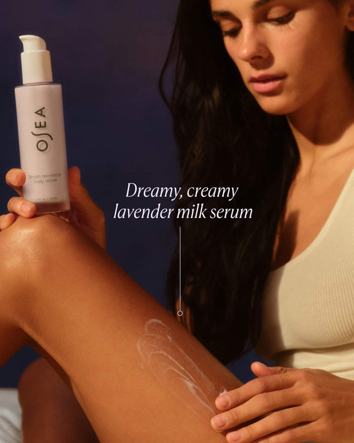 Woman applying Ojea lavender milk serum to her arm with a dark background