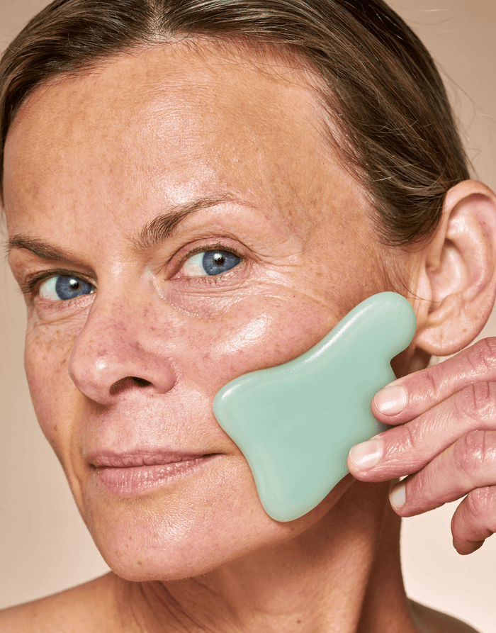 Model demonstrating lifting motion with OSEA sculpting tool along jawline
