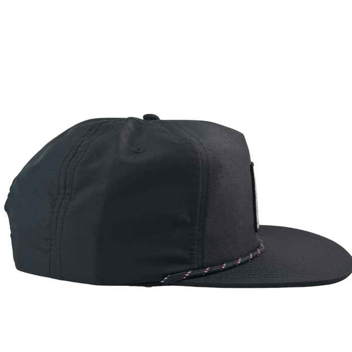 The Né dans les Alpes Unstructured Hat by Julbo Eyewear is a black baseball cap with a flat brim and decorative braided rope above the visor, blending classic style and modern appeal. #color_né-dans-les-alpes-unstructured-hat-black