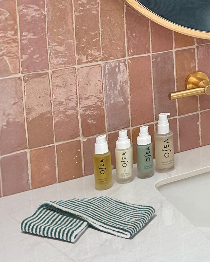 Striped reusable facial cloth on bathroom counter beside OSEA skincare products