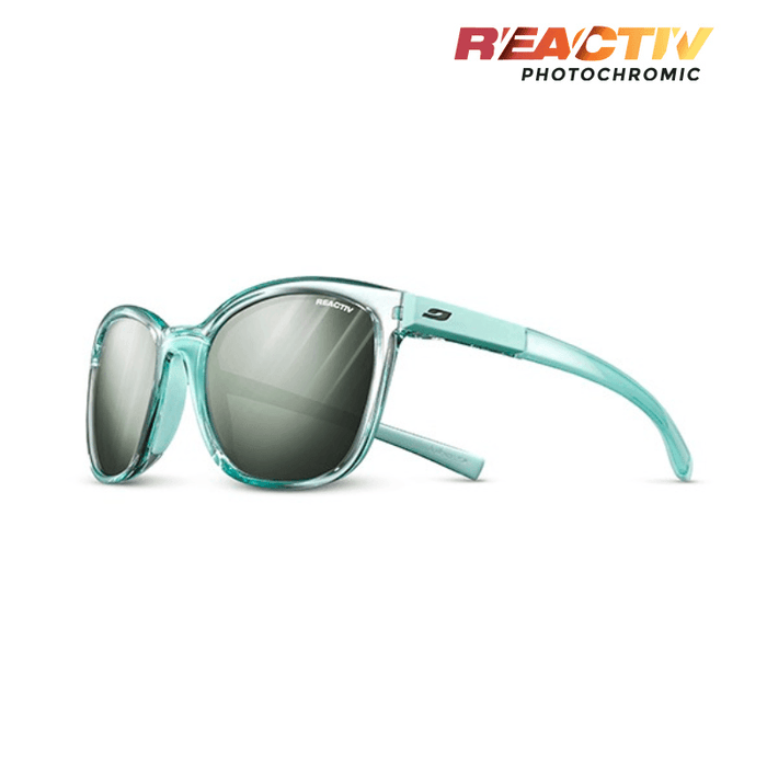 The Julbo Eyewear Spark sunglasses feature a turquoise frame and large round REACTIV photochromic lenses, blending bold style with sporty design. The REACTIV Photochromic logo is displayed in the top right corner. #color_translucent-ice-blue-with-reactiv-glare-control-1-3-lens