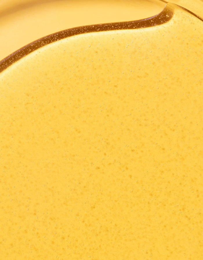 Golden body oil texture close-up showing lightweight, nourishing consistency