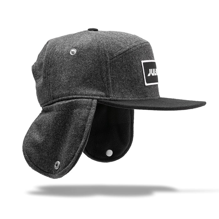 The Julbo Eyewear Woodsman Hat features dark gray earflaps with a black visor and a front patch with white text. Buttoned ear flaps provide extra warmth, making it ideal for cold weather. #color_julbo-woodsman-hat-charcoal