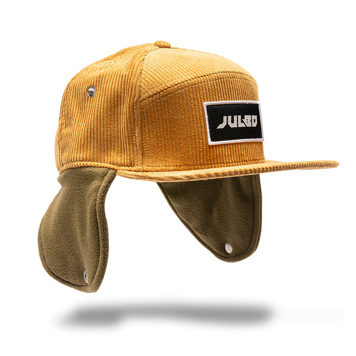 The Julbo Eyewear Woodsman Hat features mustard yellow corduroy, olive green fleece ear flaps, and a black JULBO patch—ideal for cold weather. Shown on a white background. #color_julbo-woodsman-hat-tan